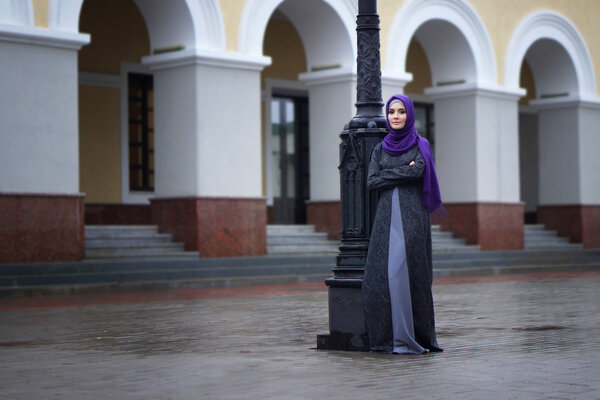 street photo a beautiful Muslim woman in traditional dress on the background of the European building