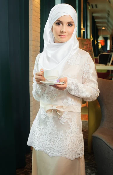 Muslimsk kvinna i en vit brudklänning med en kopp te i handen — Stockfoto