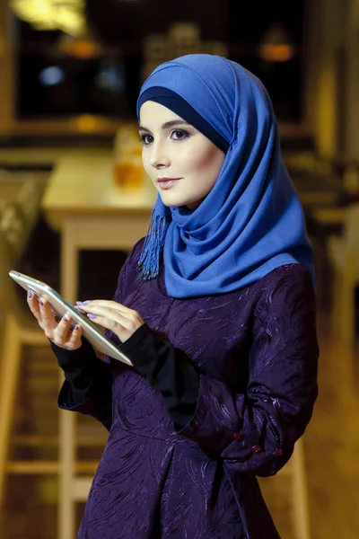 Vacker muslimsk kvinna i traditionella kläder med elektroniska tablett i händer — Stockfoto
