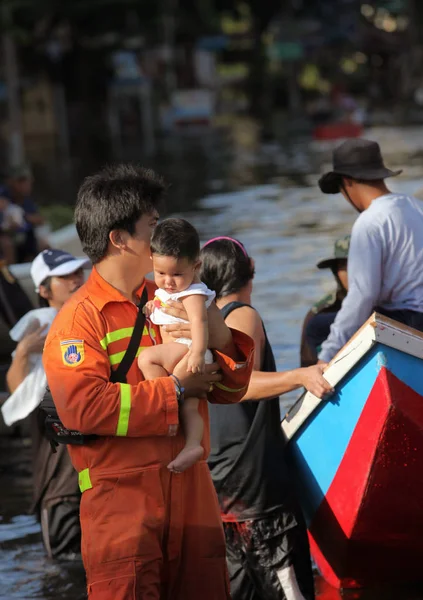 Tayland, Bangkok - Kasım 2011: Tayland bir sel sırasında onun kollarında bir bebek tutan kurtarıcı