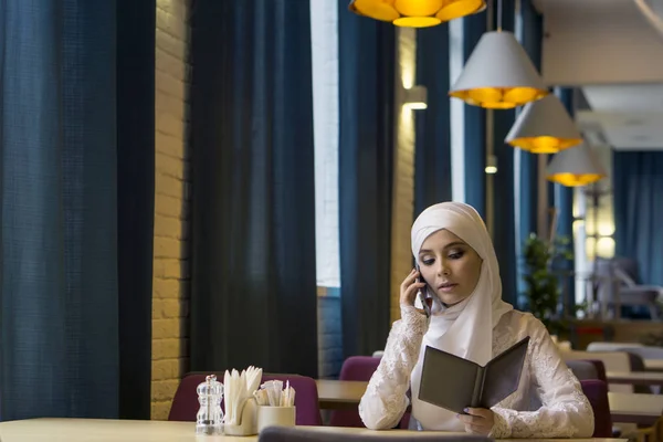 Исламская красивая девушка разговаривает по телефону в ресторане — стоковое фото