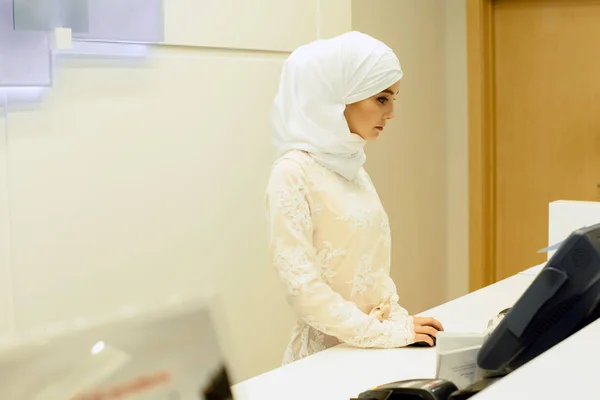 美丽的穆斯林，酒店管理员，在接待工作 免版税图库照片