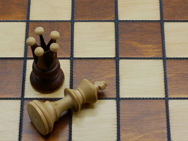 Checkmate: Uma rainha ao lado de um rei derrotado em um tabuleiro de xadrez — Fotografia de Stock