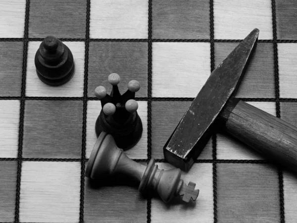 Xeque-mate brutal: martelo ao lado de um rei derrotado em um tabuleiro de xadrez, monocromático — Fotografia de Stock