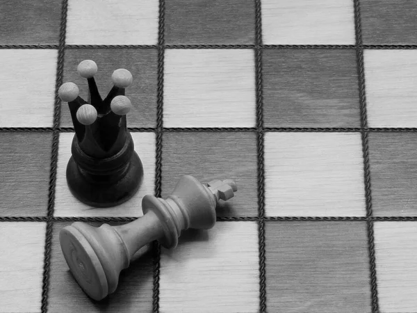 Checkmate: Uma rainha ao lado de um rei derrotado em um tabuleiro de xadrez, monocromático — Fotografia de Stock