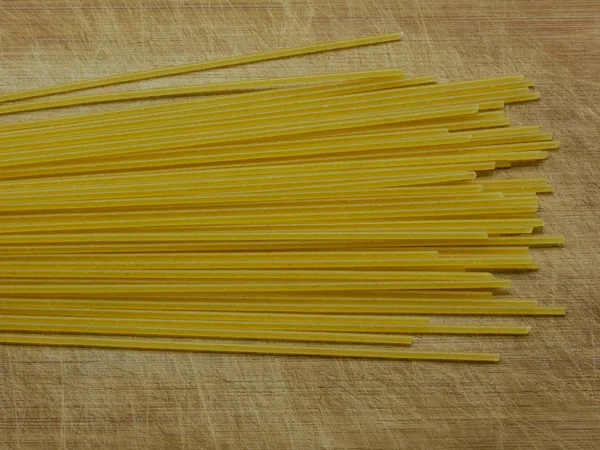 Primer plano de espaguetis sin cocer en un tablero de madera rayada, vista superior — Foto de Stock