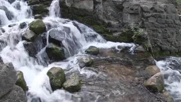 Nahaufnahme eines kleinen Wasserfalls mit bemoosten Felsen — Stockvideo