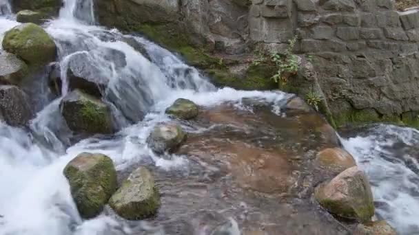 Nahaufnahme eines kleinen Wasserfalls mit bemoosten Felsen — Stockvideo