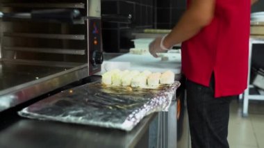 Suşi ustası lezzetli ekmekler pişiriyor. Şeffaf steril eldivenli Asyalı adam mutfaktaki beyaz masada birlikte yuvarlanıyor. Pirinç ve balıklı börekler akşam yemeğinde satışa hazır..