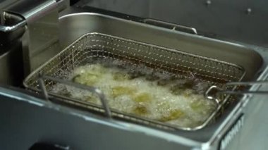 Yağlı yağ kaynıyor ve parlak gümüş rengi fritözü yakından görüyor. Lezzetli börekler yemek için. Suşi hazırlama aşamalarından biri..