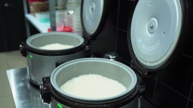 İki büyük, açık gümüş pirinç tenceresi siyah fayans zemininde parlak masanın üzerinde duruyor. Ekmekler için beyaz pirinç pişirdikten sonra soğur. Restoranlarda suşi pişirme kavramı.