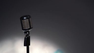 Profesyonel konser klasik mikrofon kaydı için ya da karanlık boş retro kulübünde seyircilerle konuşmak için. Sahne ışıkları soldaki krom mikrofonda gri arkaplanda parlıyor.