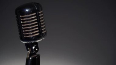 Profesyonel konser klasik mikrofon kaydı için ya da karanlık boş retro kulübünde seyircilerle konuşmak için. Sahne ışıkları soldaki krom mikrofonda gri arkaplanda parlıyor.
