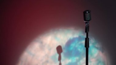 Profesyonel konser klasik mikrofon kaydı için ya da karanlık boş retro kulübünde seyircilerle konuşmak için. Işıklar çok renkli arkaplanda krom mikrofonda parlıyor..