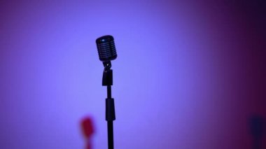 Profesyonel konser klasik mikrofon kaydı için ya da karanlık boş retro kulübünde seyircilerle konuşmak için. Kırmızı ve mavi arka plandaki krom mikrofonda ışıklar değişiyor ve parlıyor..