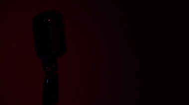 Profesyonel konser klasik mikrofon kaydı için ya da karanlık boş retro kulübünde seyircilerle konuşmak için. Sahne ışıkları eflatun mavisi arka planda krom mikrofon üzerinde parlıyor.