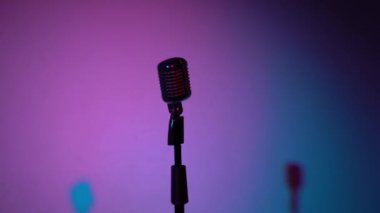 Profesyonel konser klasik mikrofon kaydı için ya da karanlık boş retro kulübünde seyircilerle konuşmak için. Sahne ışıkları ortadaki krom mikrofonda çok renkli arkaplanda parlıyor.