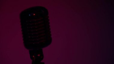 Profesyonel konser klasik mikrofon kaydı için ya da karanlık boş retro kulübünde seyircilerle konuşmak için. Mor-leylak ışığı yanıyor. Sahne ışıkları krom mikrofonda parlıyor.