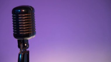 Metalik konser klasik parlayan mikrofon kaydı için ya da karanlık boş retro kulübünde seyircilere hitap etmek için. Sahne ışıkları mor arka planda soldaki krom mikrofonda parlıyor.. 