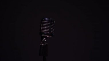 Profesyonel konser klasik mikrofon kaydı için ya da karanlık boşlukta seyircilerle konuşmak için yakın çekim. Kırmızı, beyaz ve yeşil ışıklar siyah arka planda krom retro mikrofon üzerinde parlıyor.