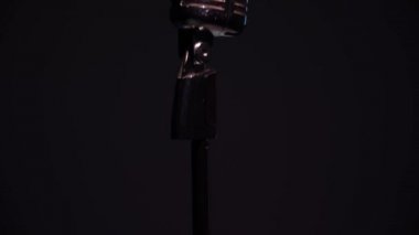 Siyah arka planda beyaz spot ışıkları krom retro mikrofonda parlıyor. Profesyonel konser klasik mikrofon kaydı için ya da karanlık boş bir kulüpte seyircilerle konuşmak için.. 