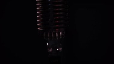 Profesyonel konser klasik mikrofon kaydı için ya da karanlık boş retro kulübünde seyircilerle konuşmak için. Kırmızı ve beyaz spot ışıkları siyah arkaplanda bir krom mikrofon üzerinde parlıyor.