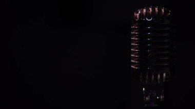 Kayıt için profesyonel vintage parlayan mikrofon ya da izole edilmiş karanlık alanda seyircilere hitap etmek. Kırmızı ve beyaz spot ışıkları siyah arkaplanda krom retro mikrofon üzerinde parlıyor..