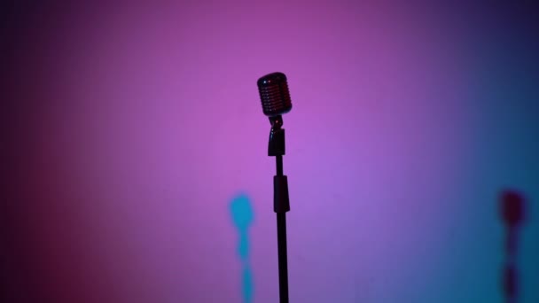 专业的老式闪光话筒供录音或在黑暗的空复古俱乐部的舞台上发言 聚光灯照射在中间的彩色麦克风上 背景是多色的 摄像机来了 — 图库视频影像