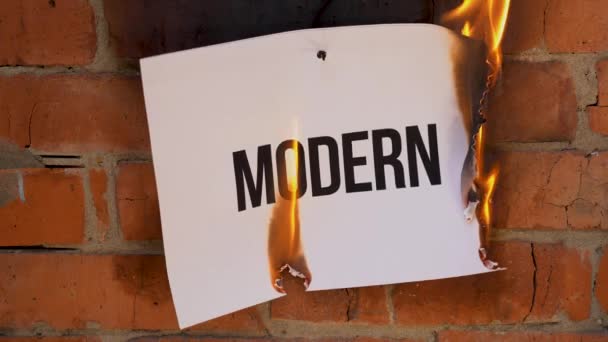L'inscription sur une feuille blanche de format A4 sur le fond d'un mur de briques orange. Le papier avec le mot noir Modern brûle, fume et se transforme en cendres. Concept d'entreprise .