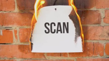 Beyaz bir A4 tablosundaki yazı turuncu bir duvarın arka planına karşı. Siyah taramalı kağıt yanıyor, duman çıkıyor ve küle dönüşüyor. İş konsepti.