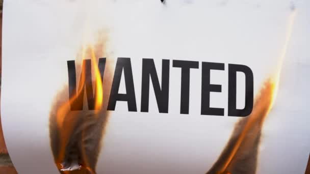L'inscription sur une feuille blanche de format A4 sur le fond d'un mur de briques orange. Le papier avec le mot noir Recherché brûle, fume et se transforme en cendres. Concept d'entreprise .