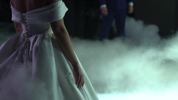 穿着漂亮的豪华白衣的漂亮女人站在靠近地面的毛茸茸的浓烟中 在幸福的婚姻生活中 相爱的夫妻 新娘和新郎正在准备婚舞 — 图库视频影像
