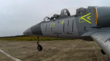 İniş pistine ya da eski boş havaalanının pistine koyu bulutlu bir gökyüzüne doğru inen gri bir savaş uçağı. Şasi yere değiyor. Sol kanattan yaklaş.
