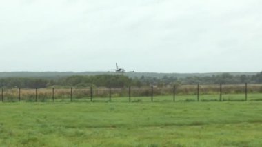 Gri mavi eğitim jeti havalimanının zemininden hızla ve alçaktan uçar, ayağa kalkar ve bulutlu bir gökyüzüne karşı fıçı manevrası yapar. Pistte tehlikeli bir numara. Rus bayrağı.