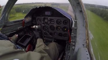 Pilot tutma ve kontrol dümeni. Gri mavi bir jet uçağı yerden çok hızlı ve alçaktan uçar ve yukarı yükselir. Karanlık bulutlu bir gökyüzüne karşı sola dönün. Kokpit ve gösterge paneli görüntüsü kapat.