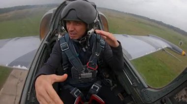 Uçakta dans eden ikinci pilot. Bulutlu bulutlu gökyüzüne doğru hızla ve alçaktan uçan gri savaş uçağı. Tehlikeli bir numara. Kokpitten iç görünüş.