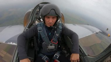 Pilot kask takan beyaz, yakışıklı bir adam. Erkek rahatlar ve hareketler yapar keçi ya da rockçı. Saha ve nehir üzerinde uçan gri bir savaş uçağı. Kokpitten iç görünüş.