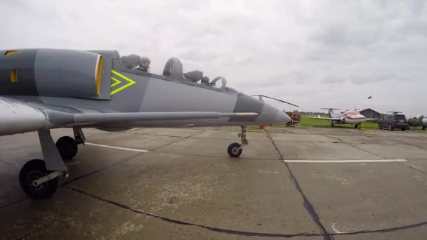 在阴天 一架灰色的蓝色战斗机正在飞往老机场的跑道上训练 飞机在平面背景上的混凝土板上运动 从右边看近点 — 图库视频影像