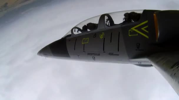 一架灰色的蓝色训练战斗机在绿地上空飞行 在天空乌云笼罩的背景下左右摆动 从左边看近点 — 图库视频影像