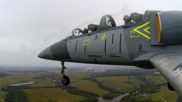 灰色の青い戦闘機は川の上を飛行し 野外では暗い曇りの空に対して着陸装置を放出した 左翼端からの眺め — ストック動画