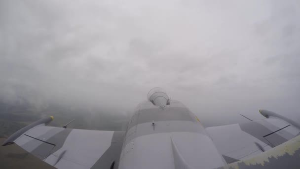 灰色の戦闘機は白い厚い雲の中を飛ぶ 戦闘機は左に傾けられ 曇りの日に飛行場の上を飛ぶ 尾びれからのトップビューを閉じます ステルスコンセプト — ストック動画