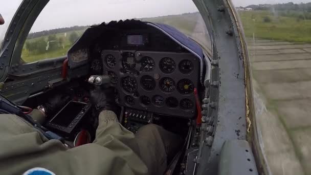 パイロットは舵を握って制御する 灰色の戦闘ジェット機は飛行場の地面の上を迅速かつ低飛行し 曇った空に対してバレルロール操縦を行います コックピット近くの景色 — ストック動画