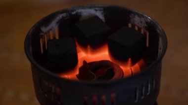 220 voltluk elektrik prizinin özel bir sobasında kömür tutuşturuluyor. 3 siyah kömür kömürü, sicak sicakliktan sicak sicaklikta sicak bir sarmalda sicak ve sicak bir sekilde yaklasiyor..