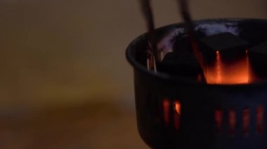Güzel bir bej nargileden beyaz duman dumanı yükselirken siyah arka planda esiyor. Kahverengi bir kase ve metal bir kaloud nargileye konur..