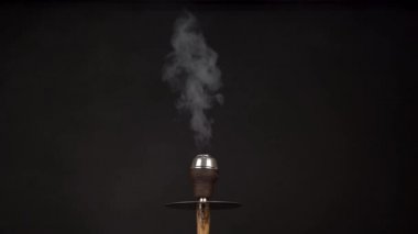 Güzel bir bej nargileden beyaz duman dumanı yükselirken siyah arka planda esiyor. Buharlı lokomotifin borusuna çok benziyor. Yavaş çekim.