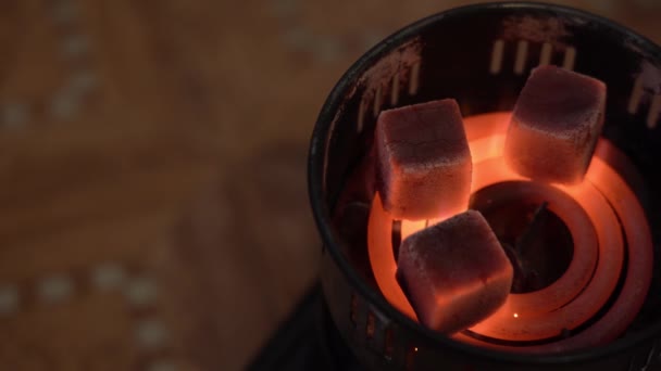一个人把空的圆形金属大声放在3个黑色燃烧的正方形煤上 在一个红色的螺旋线上 一个旧的生锈的便携式电炉靠近 顶视图 Hookah概念 — 图库视频影像