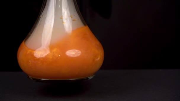 Mens Schudt Een Glazen Schaal Met Oranje Voedselverf Water Een — Stockvideo