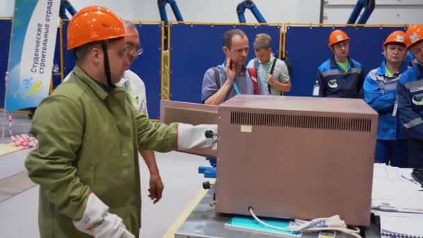 ロシア 8月07 2019 白人労働者男性は工場を背景に職場の研削盤に金属棒を研削します 1人の男は火花から頭の上に特別な保護緑のジャケット 白い顔のマスク 赤いヘルメットを着用 — ストック動画
