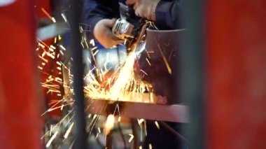 Bir işçi tüm güvenlik gereksinimlerine göre kıyafet giyer, özel zımpara, öğütücü, sıralama ve pürüzsüz bir şekilde fabrikadaki tezgahta metal borunun kenarını kullanır. Kıvılcımlar uçar. Görüntüyü kapat.