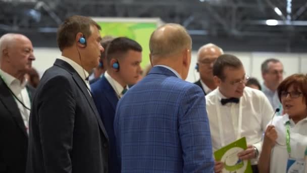 2019年8月7日 俄罗斯索契 一群带着耳机的外国商人正在仔细聆听一个关于工厂的新项目的介绍 男人穿衬衫 深色夹克 女口译员用话筒说话 室内环境 — 图库视频影像